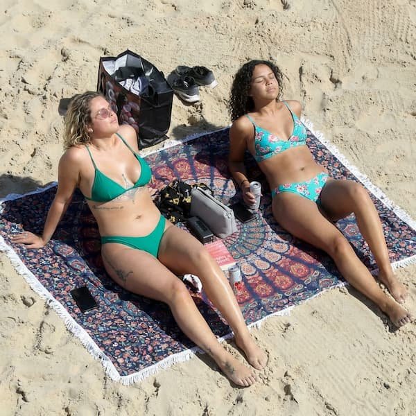 People enjoying a sunny day at a sandy beach with gentle ocean waves.
